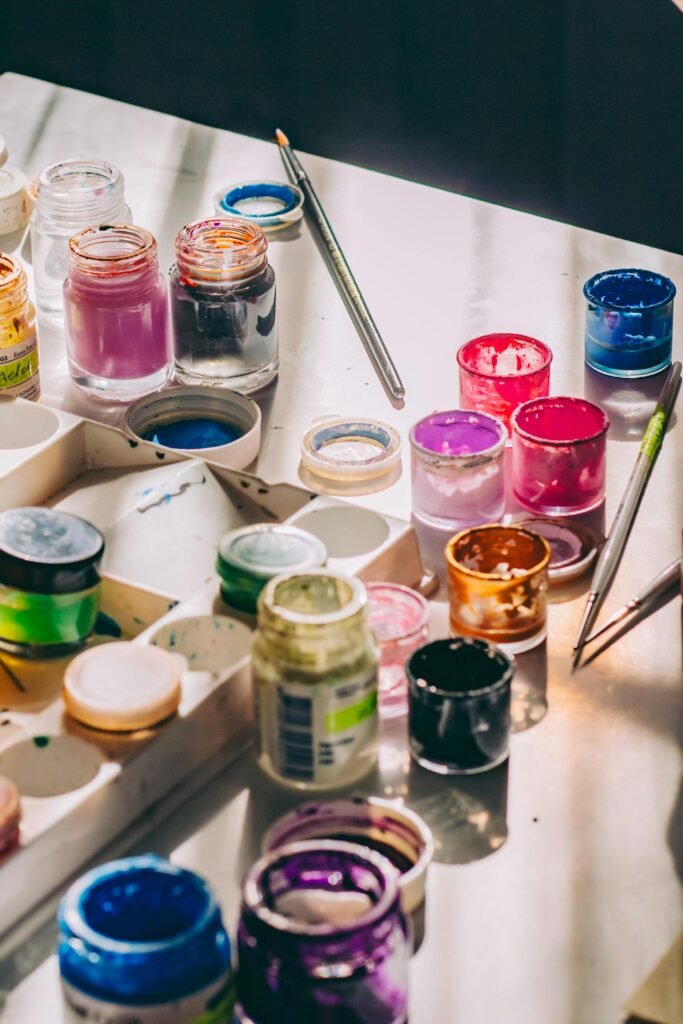 A vibrant array of acrylic paint jars and brushes on a sunlit table, perfect for creative projects.